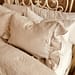 Linen bedding with ruffle edge natural neutral color French country bedroom makeover gel pillows Sleep Number bed wrought iron headboard painted white with chalk paint and all in one paint